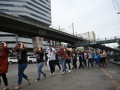 موظفو مركز تسوق يغطون رؤوسهم على طول الطريق أثناء مشاركتهم في تدريب على الزلزال في العاصمة الفلبينية مانيلا- 14 نوفمبر 2019 - AFP