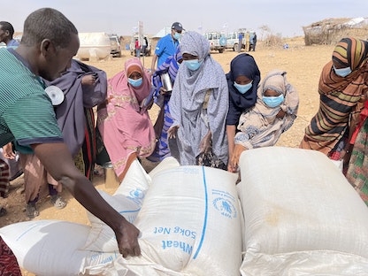 أشخاص يتلقون مساعدات إغاثية في مخيم للنازحين بالمنطقة الصومالية في إثيوبيا - 22 يناير 2022 - via REUTERS