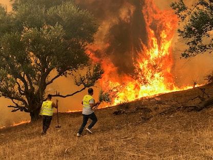 رجال يحاولون إخماد حريق في قرية إيبودرارن بمنطقة القبائل الجبلية في تيزي وزو، شرق الجزائر العاصمة، الجزائر، 12 أغسطس 2021 - REUTERS
