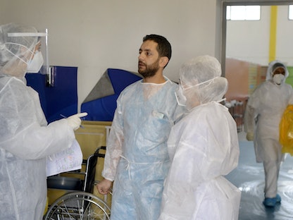 طبيب الطوارئ التونسي عبد الوهاب مغربي 35 عاماً يتحدث إلى العاملين في مستشفى مامي في مدينة أريانة بالقرب من العاصمة  - AFP