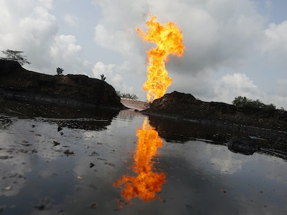 انعكاس الغاز المحروق في بركة مياه ملوثة بالزيت في محطة تدفق في أوغيلي بولاية دلتا في نيجيريا - 17 سبتمبر 2020 - REUTERS