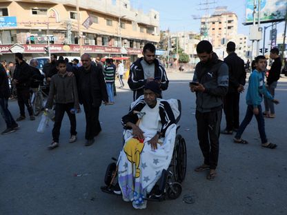 رجل على كرسي متحرك بينما يفر الفلسطينيون من منازلهم بعد أن أمرهم الجيش الإسرائيلي بإخلاء مخيم البريج في وسط قطاع غزة. 26 ديسمبر 2023 - Reuters
