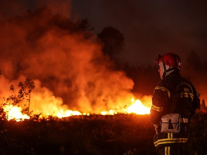 رجل إطفاء ينظر للنيران، التي اندلعت بسبب موجات حر اجتاحت البلاد، في غابة بالقرب من لوشاتس في جيروند، جنوب غرب فرنسا. 17 يوليو 2022. - AFP