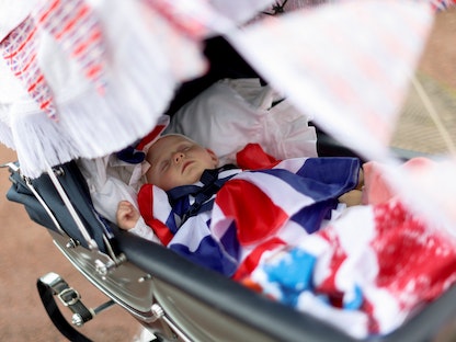 طفلة تنام في عربة أطفال ببلدة موركامب بمقاطعة لانكستر شمال غرب إنجلترا- 5 يونيو 2022 - REUTERS