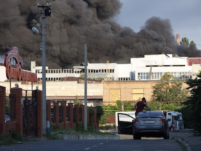 رجل يشاهد سحابة دخان بعد ضربة صاروخية على مستودع لشركة صناعية وتجارية في أوديسا– 16 يوليو 2022 - AFP