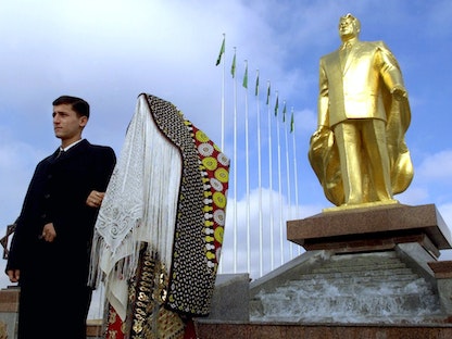 زوجان يلتقطان صورة أمام تمثال للرئيس صابر مراد نيازوف في عشق أباد عاصمة تركمانستان. 28 ديسمبر 2002 - REUTERS