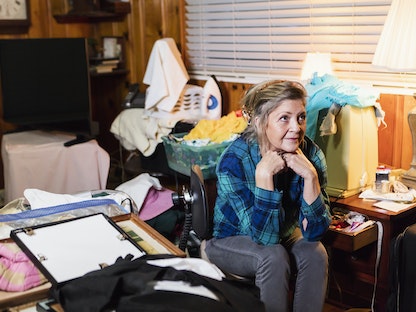 امرأة جالسة في غرفتها غير المرتبة وتبدو عليها علامات اضطراب التخزين - Getty Images