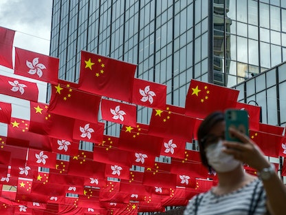 تلتقط صورة "سيلفي" مع أعلام للصين وهونغ كونغ في المدينة - 30 يونيو 2021 - Bloomberg
