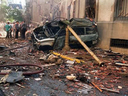 رجال شرطة وعمال إنقاذ يقفون بالقرب من سيارات مدمرة وحطام بعد انفجار قنبلة في السفارة الإسرائيلية في بوينس آيرس. 17 مارس 1992 - AFP
