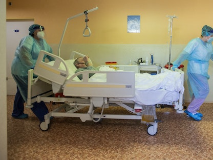 ممرضتان ترتديان معدات الوقاية الشخصية تدفعان مريضاً بفيروس كورونا في أحد مستشفيات التشيك - AFP