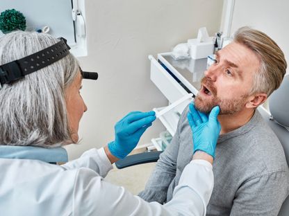 طبيبة تفحص فم وحلق أحد المرضى. 8 مارس 2023 - AFP