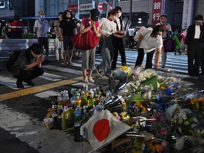 يابانيون يضعون الورود مكان اغتيال رئيس الوزراء السابق شينزو آبي أمام محطة قطارات مدينة نارا غربي اليابان - 8 يوليو 2022 - AFP