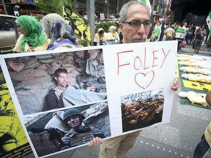 رجل يحمل لافتة تخليداً لذكرى الصحافي الأميركي جيمس فولي خلال مظاهرة في تايمز سكوير بنيويورك. 22 أغسطس 2014 - REUTERS