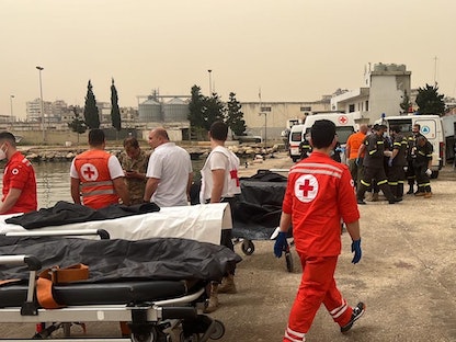 فرق الصليب الأحمر والدفاع المدني خلال عملها في مرفأ طرابلس بعد العثور على عدد من الجثث التي غرقت في مركب الهجرة شمال لبنان- 24 أبريل 2022