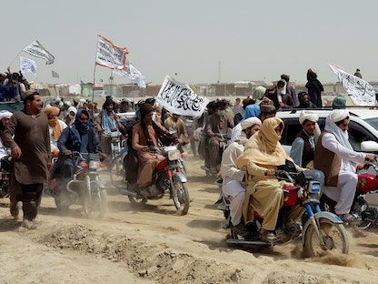 أشخاص يحملون أعلام طالبان، يتجمعون بالقرب من نقطة عبور في بلدة شامان الحدودية الباكستانية الأفغانية، باكستان- 14 يوليو 2021 - REUTERS