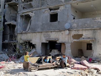 أطفال فلسطينيون يجلسون بالقرب من أنقاض المنازل التي دمرت في غارات جوية إسرائيلية على غزة، 9 يونيو 2021 - REUTERS