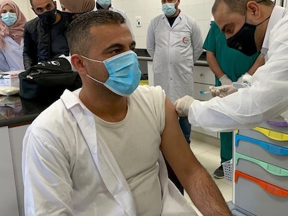 تطعيم أحد أفراد الطواقم الطبية الفلسطينية. - وكالة الأنباء والمعلومات الفلسطينية "وفا"