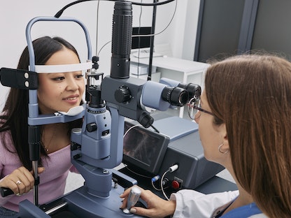 طبيبة عيون تفحص امرأة في عيادتها - Science Photo Library