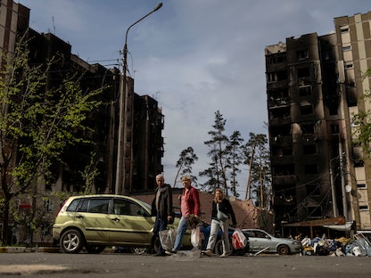 أوكرانيون يسيرون قرب مبان متضررة بعد قصف روسي على منطقة سكنية في إربين قرب العاصمة كييف - 7 مايو 2022 - REUTERS