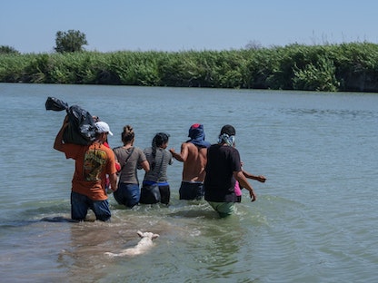مهرّبون يساعدون مهاجرين على عبور نهر ريو جراندي إلى الولايات المتحدة من المكسيك - 28 يوليو 2022 - Bloomberg