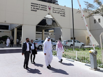 أشخاص يمرون أمام وزارة العدل والشؤون الإسلامية والأوقاف البحرينية  - REUTERS