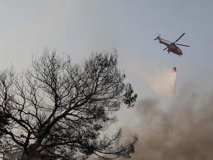  طائرة هليكوبتر لمكافحة الحرائق تسقط الماء مع اندلاع حريق هائل في ضاحية فاريمبومبي شمال أثينا، اليونان، 4 أغسطس 2021 - REUTERS