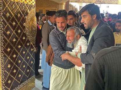 أشخاص يساعدون قريب أحد الضحايا في موقع انفجار داخل مقر شرطة في مسجد بمدينة بيشاور الباكستانية- 30 يناير 2023 - AFP