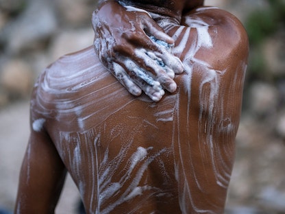 رجل يستحم بالمياه العذبة التي تم جمعها من بئر في بورت أو برنس في هايتي. 12 أكتوبر 2022. - REUTERS