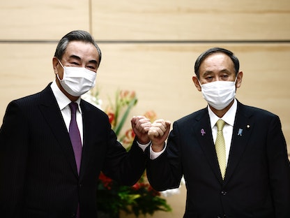 رئيس الوزراء الياباني يوشيهيدي سوغا (يمين) ووزير الخارجية الصيني وانغ يي خلال لقائهما في طوكيو، 25 نوفمبر 2020 - REUTERS
