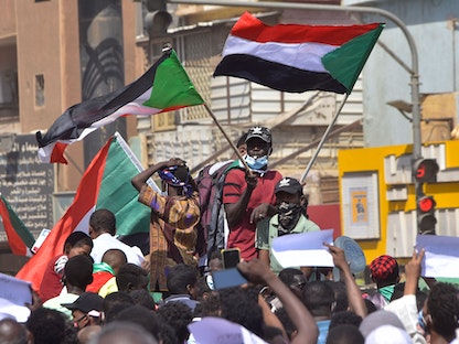 متظاهرون يلوحون بالأعلام السودانية في الخرطوم.  - AFP