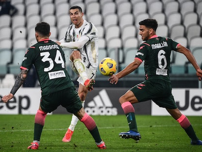 نجم يوفنتوس البرتغالي كريستيانو رونالدو يسدد الكرة من بين لاعبيّن من نادي فيرونا - AFP