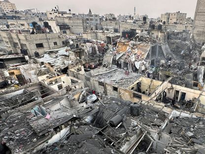 أشخاص يبحثون بين أنقاض مباني فلسطينية دمرتها غارة جوية إسرائيلية في رفح جنوبي قطاع غزة- 12 ديسمبر 2023 - Reuters