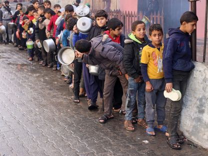 أطفال فلسطينيون يقفون في طابور لتلقي طعام تقدمه جمعية خيرية في رفح جنوب قطاع غزة. 14 ديسمبر 2023 - REUTERS
