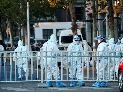يرتدون بدلات واقية ويحرسون محيط مجمع سكني مغلق بعد تفشٍّ محلي لفيروس كورونا في بكين، 11 نوفمبر 2021 - REUTERS