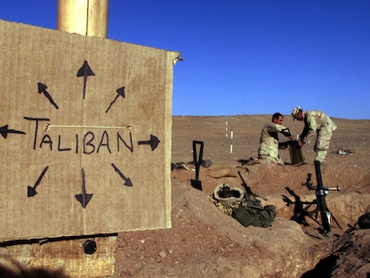 جنود أميركيون في جنوب أفغانستان بالقرب من لافتة تذكر الجميع بأن مقاتلي "طالبان" موجودون في كل مكان - 1 ديسمبر 2001 - REUTERS