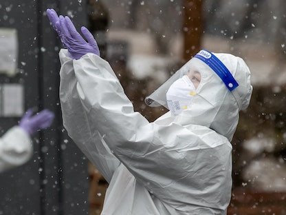 عاملة صحية ترتدي بدلة واقية تستمتع بالثلج المتساقط في موقع لفحص فيروس كورونا في سيول، كوريا الجنوبية، 12 يناير 2021 - via REUTERS