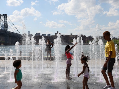 الناس يلهون بالماء في منطقة مائية في دومينو بارك حيث ضربت موجة حر المنطقة في بروكلين، مدينة نيويورك، الولايات المتحدة. 8 أغسطس 2022 - REUTERS