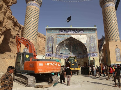 جرافة أمام مدخل مزار ديني في كربلاء بالعراق، ضمن جهود إنقاذ عالقين تحت الأنقاض- 21 أغسطس 2022 - AFP