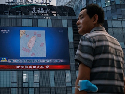 رجل يقف أمام شاشة تعرض خريطة للمواقع في جميع أنحاء تايوان حيث يجري الجيش الصيني تدريبات عسكرية، بكين - 3 أغسطس 2022 - REUTERS