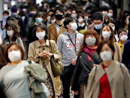 يابانيون يسيرون في الشارع وهم يرتدون أقنعة واقية وسط تفشي كورونا في العاصمة طوكيو - REUTERS