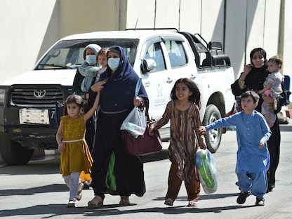امرأة أفغانية وأطفالها يسيرون باتجاه بوابة الدخول الرئيسية لمطار كابول على أمل مغادرة البلاد، 28 أغسطس 2021 - AFP