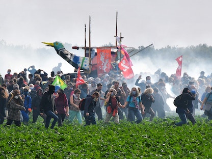 نشطاء يسيرون وسط الغاز المسيل للدموع بعد اشتباكات مع الشرطة أثناء مظاهرة ضد بناء خزان مياه للري غرب فرنسا، 29 أكتوبر 2022. - AFP
