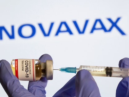 حقنة طبية للقاح كورونا أمام شعار شركة "نوفافاكس" - REUTERS