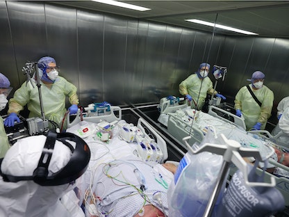 عاملون طبيون أثناء نقلهم لمصاب بفيروس كورونا (Covid-19). 10 ديسمبر 2021 - AFP