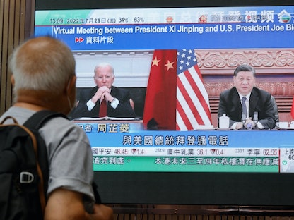 شاشة تعرض تقريراً إخبارياً بشأن اتصال الرئيس الصيني شي جين بينج ونظيره الأميركي جو بايدن في مركز تسوق بهونج كونج. 29 يوليو 2022 - REUTERS