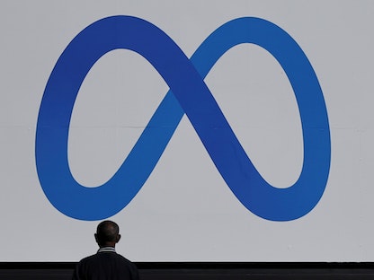 رجل يقف أمام الشعار الجديد لشركة "فيسبوك" بعد تغيير اسمها إلى "ميتا" بمقرها في كاليفورنيا - 28 أكتوبر 2021 - REUTERS