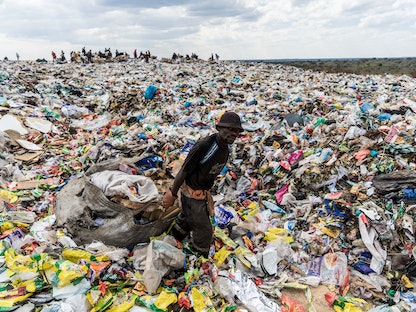  عامل يسحب كيساً في كومة من النفايات البلاستيكية  - AFP