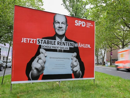 ملصق انتخابي يُظهر أولاف شولتز وزير المالية الألماني والمرشح الأعلى للحزب الاشتراكي الديمقراطي الألماني (SPD)، الذي يحمل خطاباً للتصويت بالبريد في هانوفر بألمانيا- 17 أغسطس 2021 - REUTERS