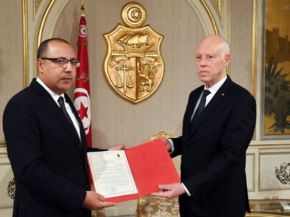 رئيس الوزراء التونسي هشام المشيشي (يسار) يتسلم خطاب التكليف بتشكيل الحكومة من رئيس الجمهورية قيس سعيّد - رئاسة الجمهورية التونسية