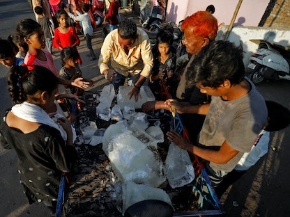 رجل يكسر كتلة من الجليد ليوزعها على سكان أحد الأحياء الفقيرة أثناء الطقس الحار في أحمد آباد - REUTERS